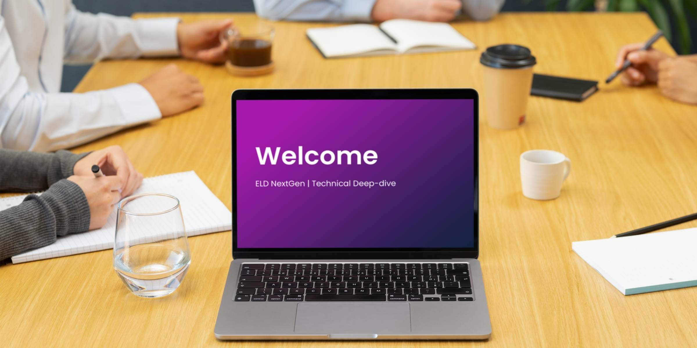 Welcome screen displayed on a laptop in a meeting room, featuring a company logo and a prompt to join the meeting.