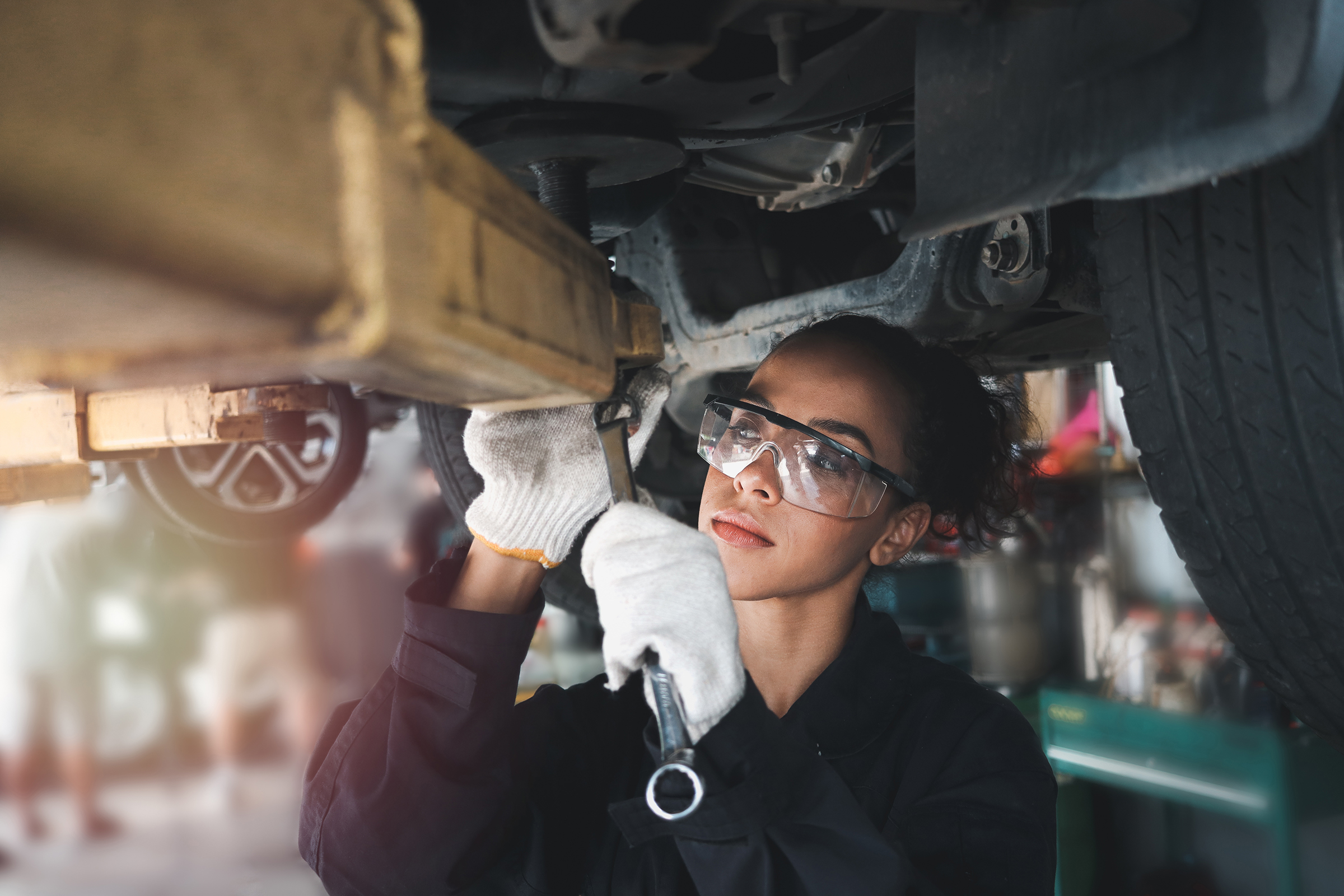 A woman in a safety suit inspects a vehicle, demonstrating automotive maintenance and safety practices.