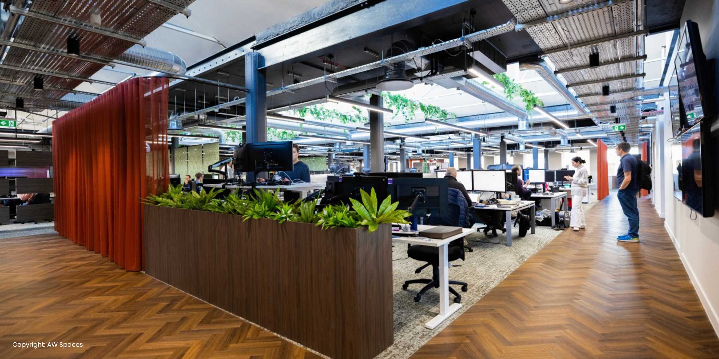 An office featuring a wooden floor and a large window, allowing natural light to illuminate the space.